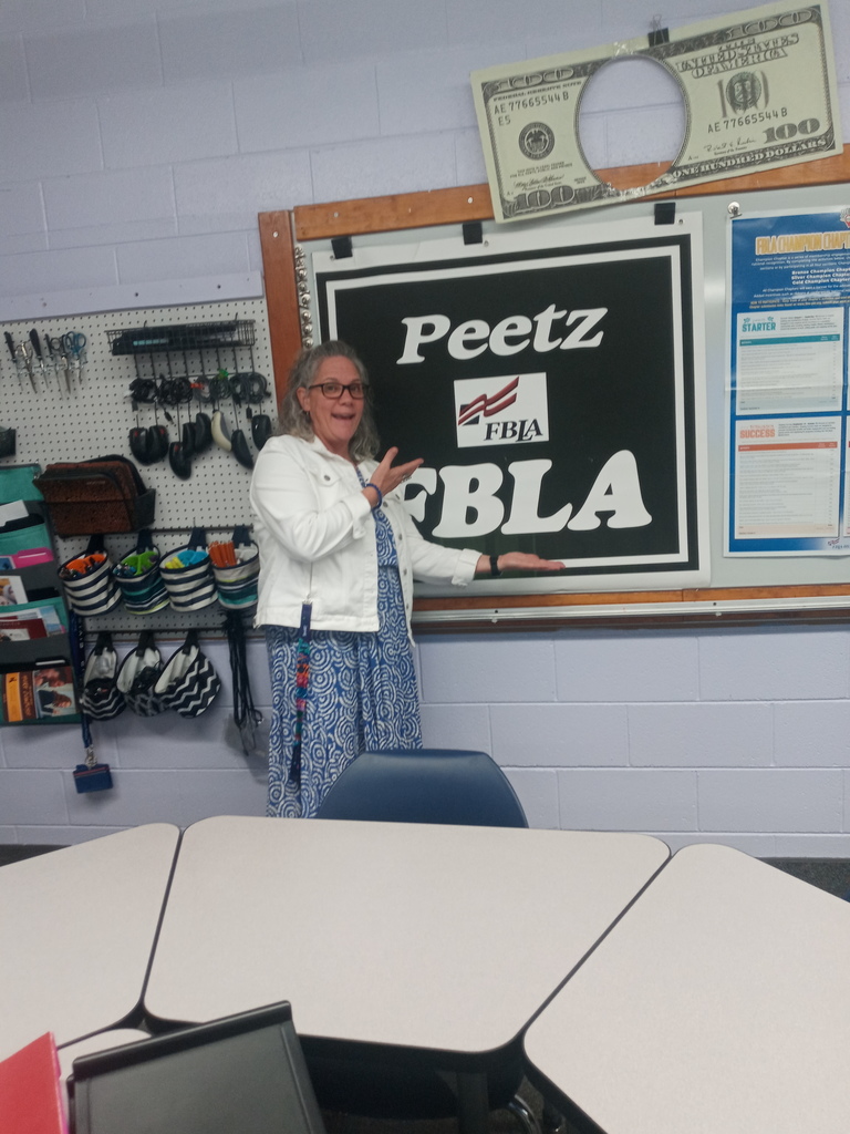 traci davenport pointing at an fbla sign.
