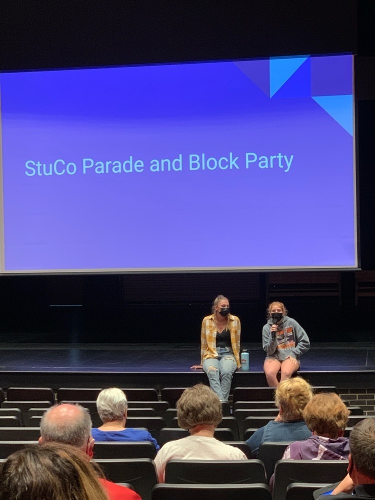 two students sitting on stage, speaking 