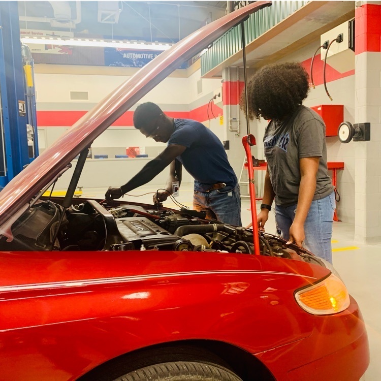 students looking underneath hood of car