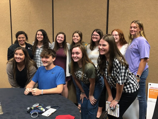 students standing in a group posing for a picture behind a table.