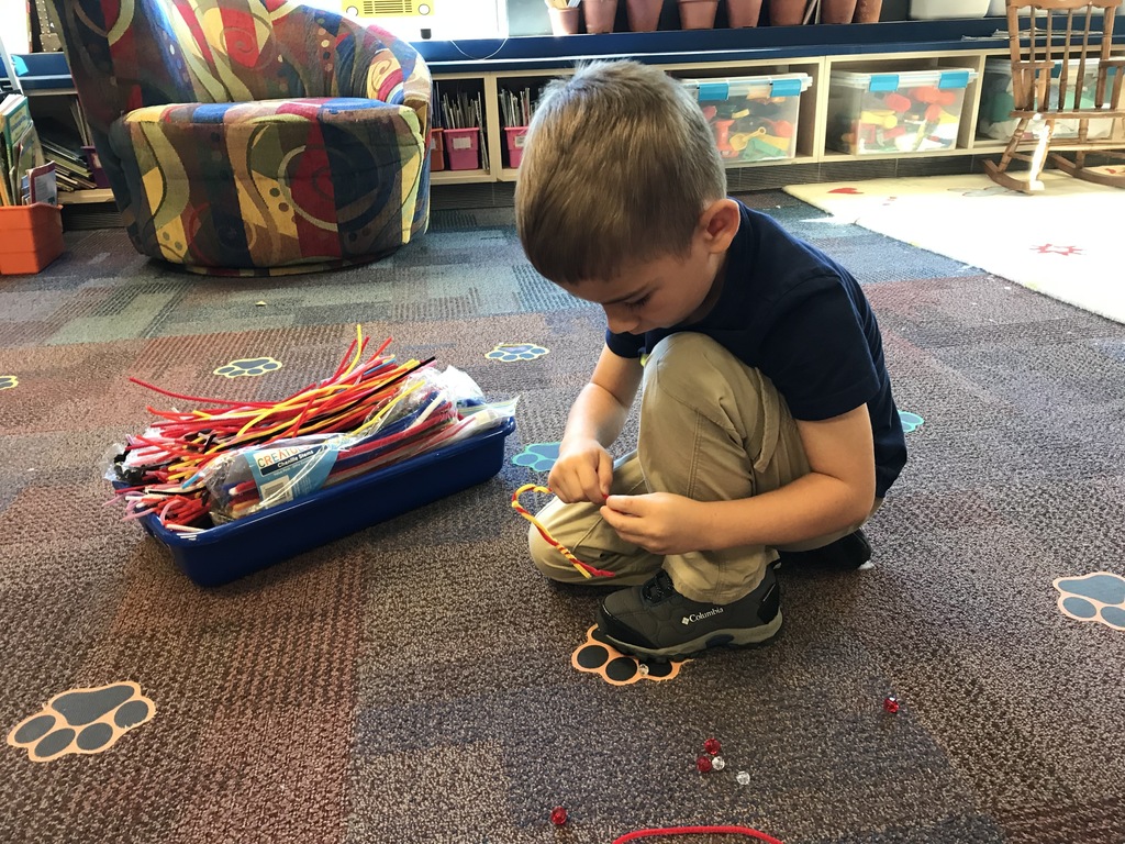 male student putting beads on pipe