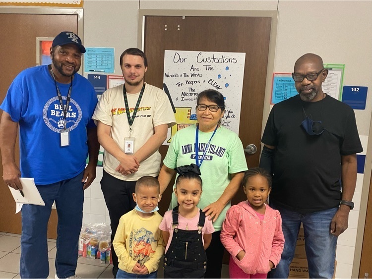 Custodians and kids pose for picture. 