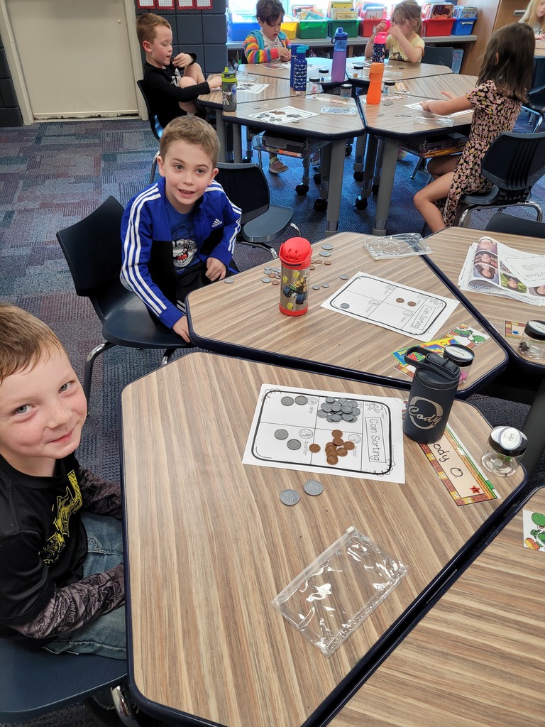 two students sitting at their desks with coins