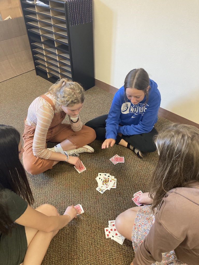 four girls sitting on the ground playing cards