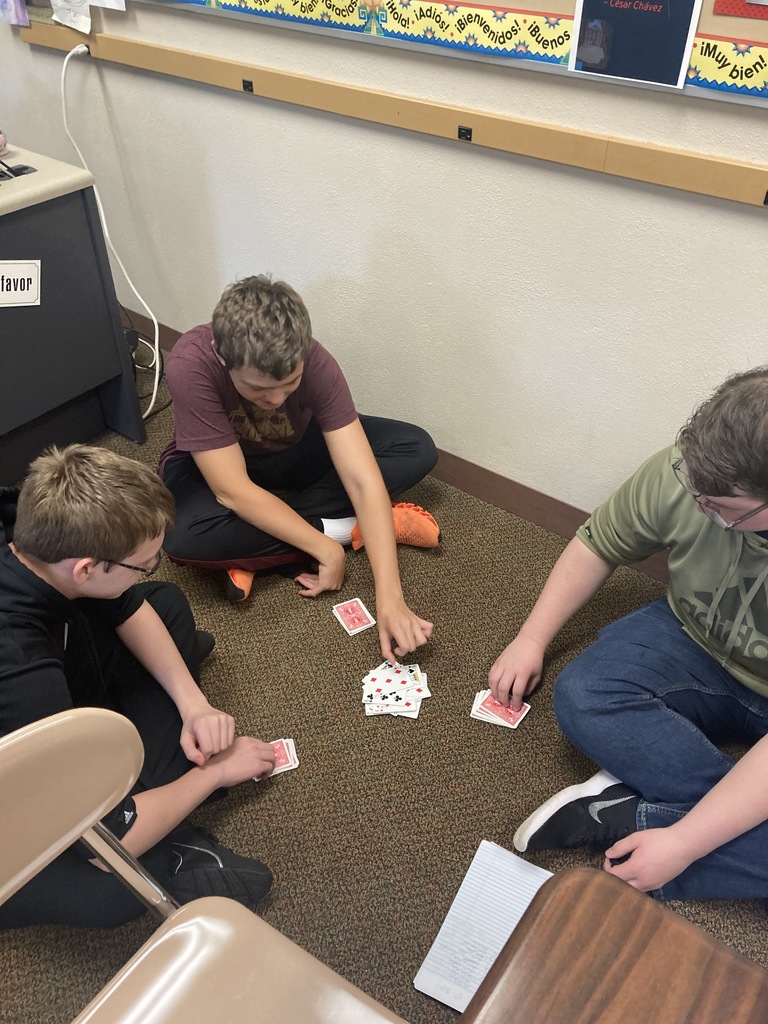 three boys sitting on the ground playin cards