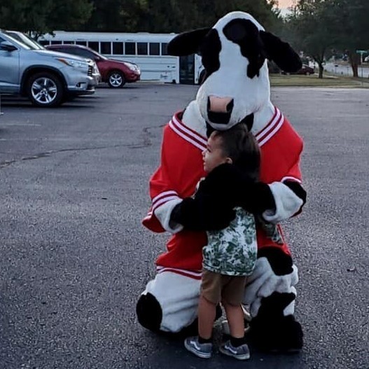 Chick Fl A Cow hugging a young student