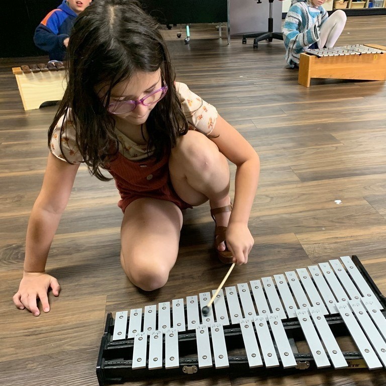 girl playing metal xylophone