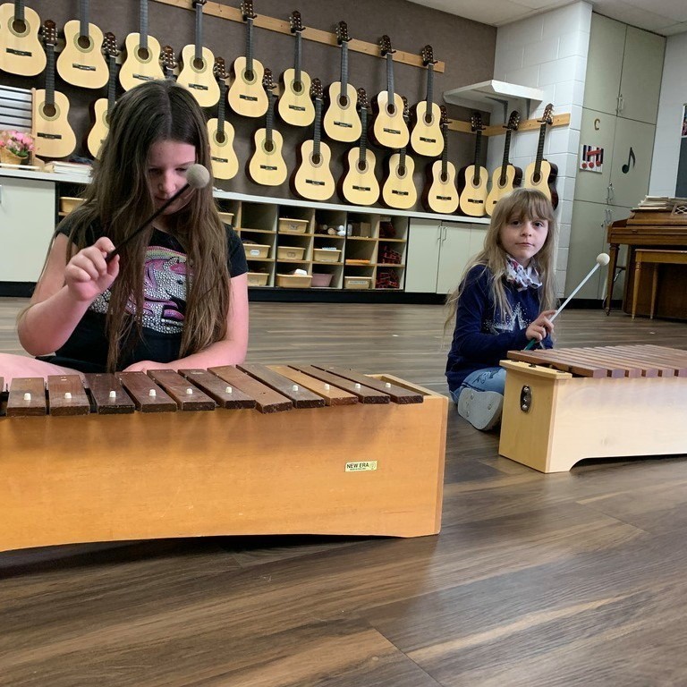 two girls playing xylophones