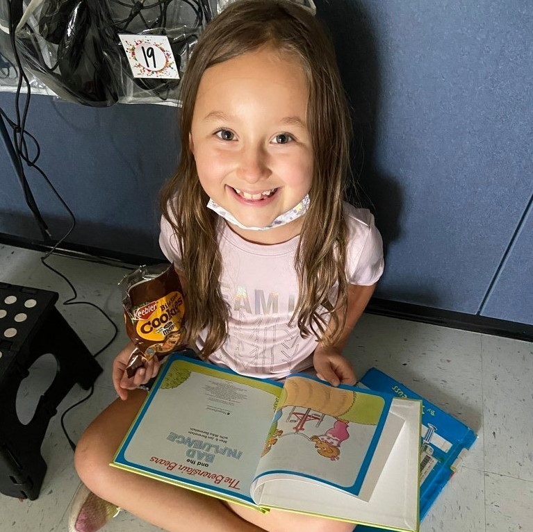 girl reading with cookie snack 