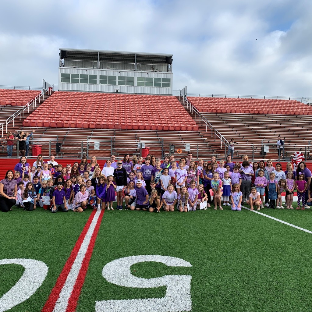 Staff & student in purple on the football field 