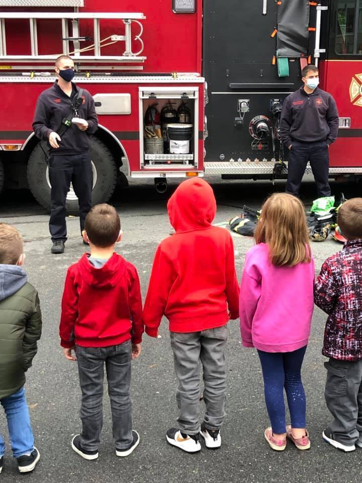 5 kids and 2 firefighters talking 