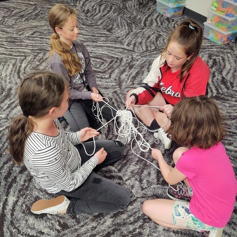 GROUP OF GIRLS UNTANGELING STRINGS