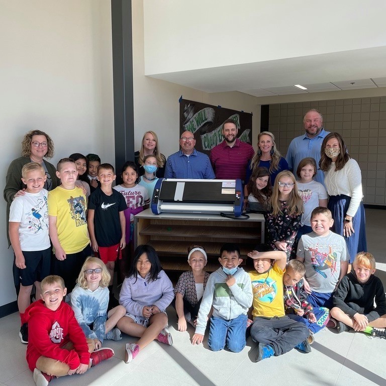 teacher and students surrounding the laminator