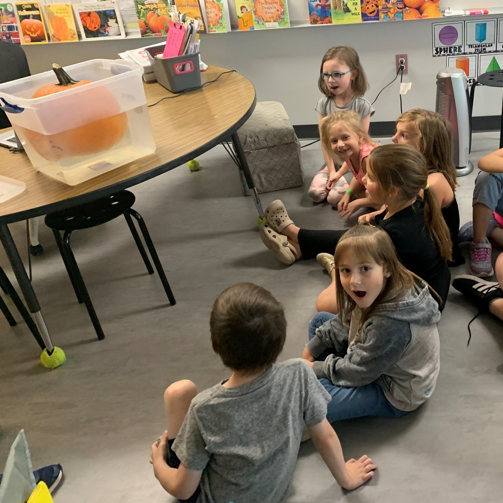 kids sitting on floor looking at pumpkin floating 