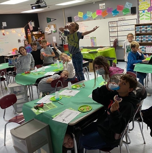 Kids at desks with plates and snacks 