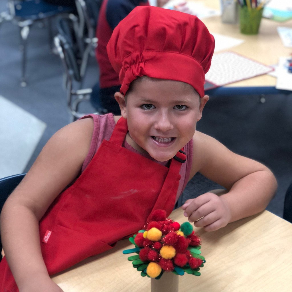 student in chefs hat with apple tree