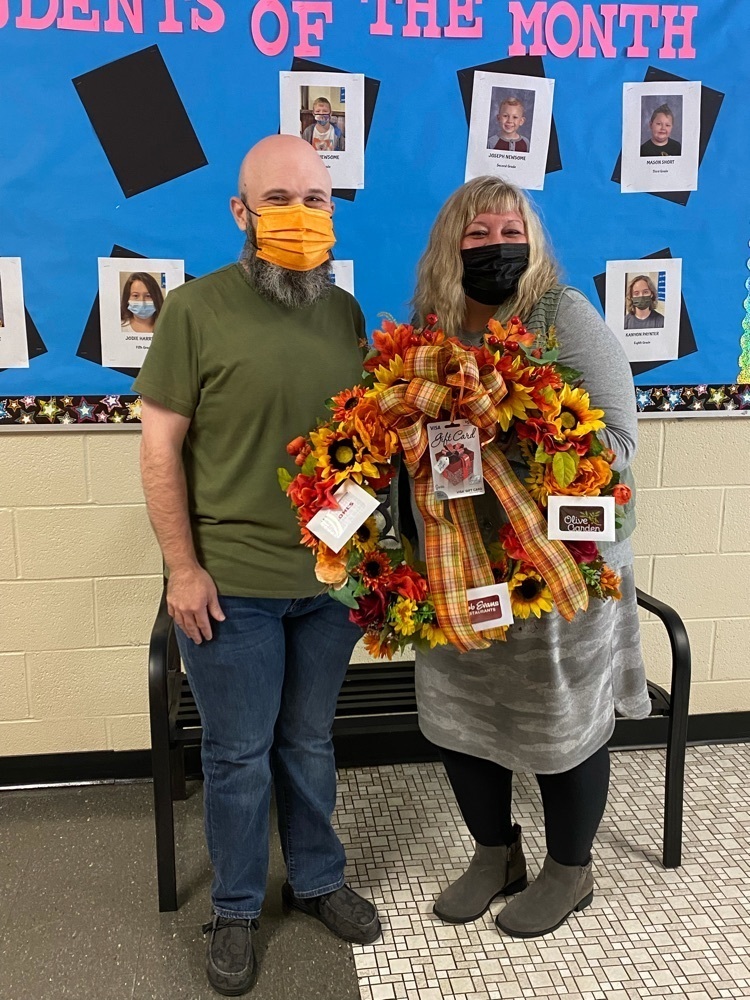 principal and teacher holding a wreath