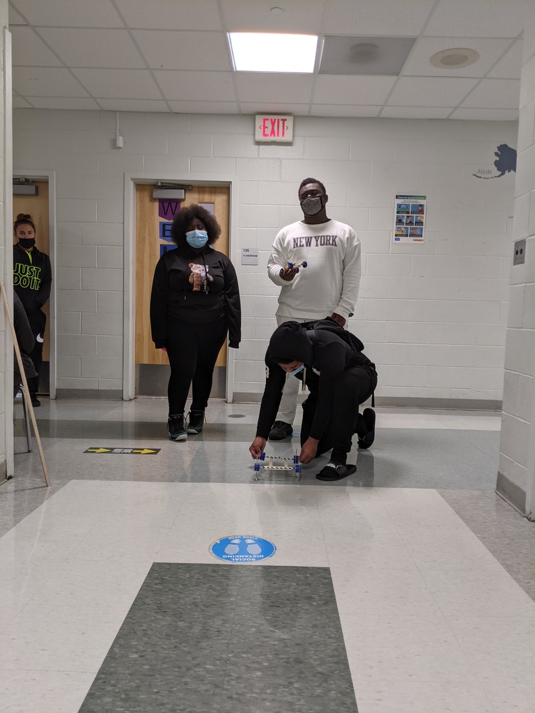 Three students testing out their rubber band powered cars. 