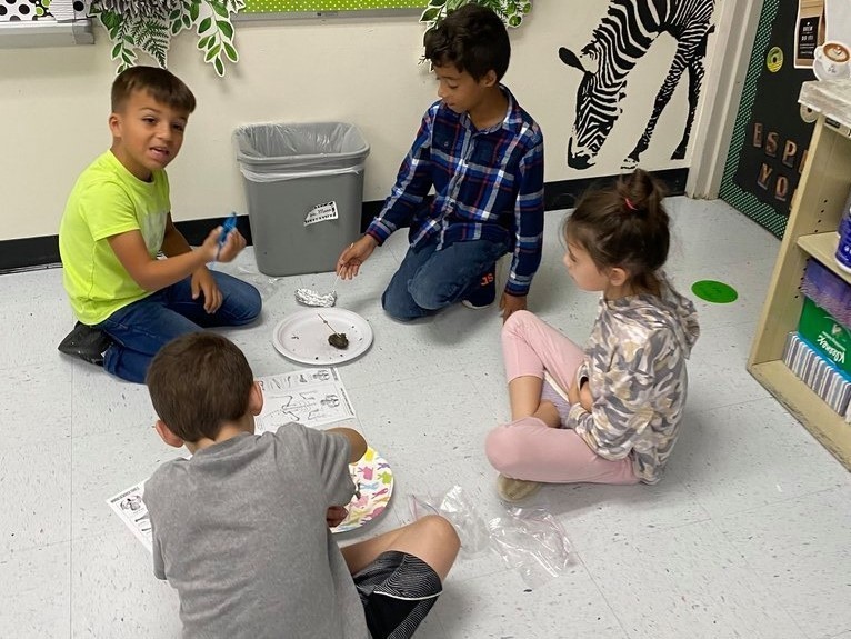 4 students dissecting owl pellets on the floor