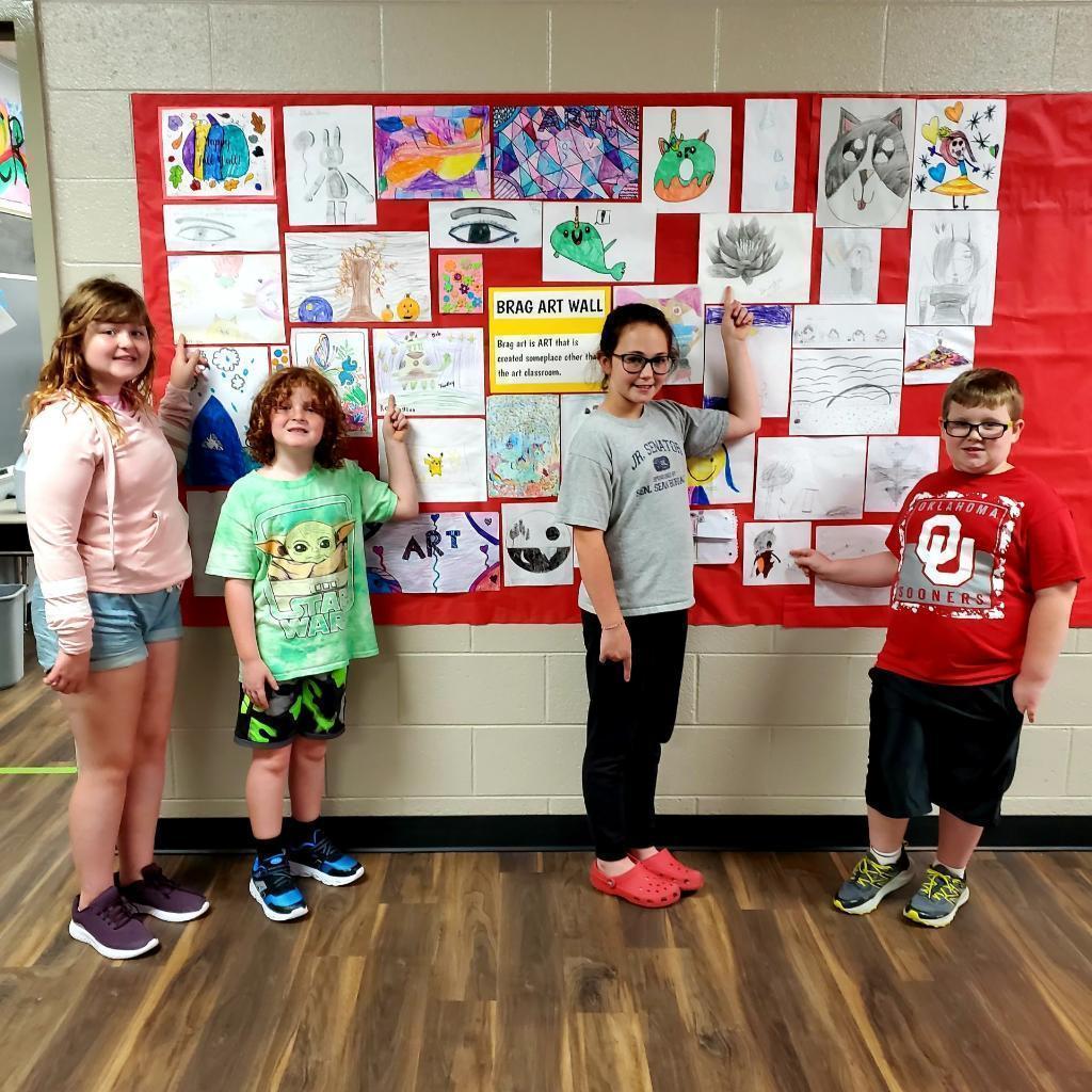 students in front of their art hanging on the wall