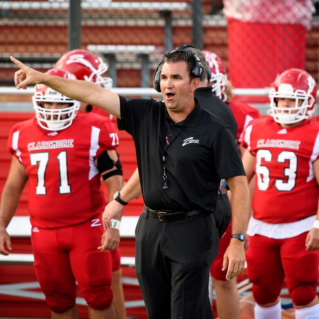 Coach hurt on sidelines with player pointing. Photo Credit: Means Photography