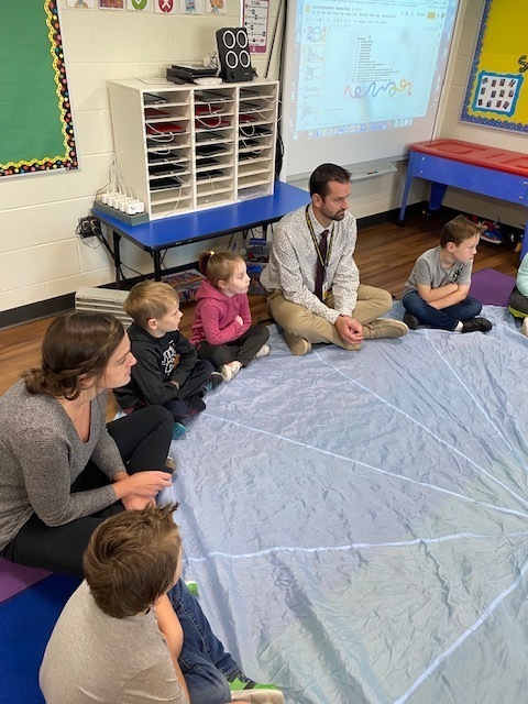 Students sitting in a circle for Rainbow Dance
