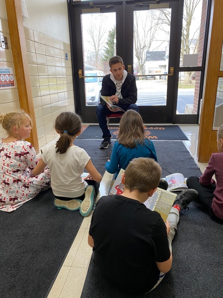 High school student reading to kids.