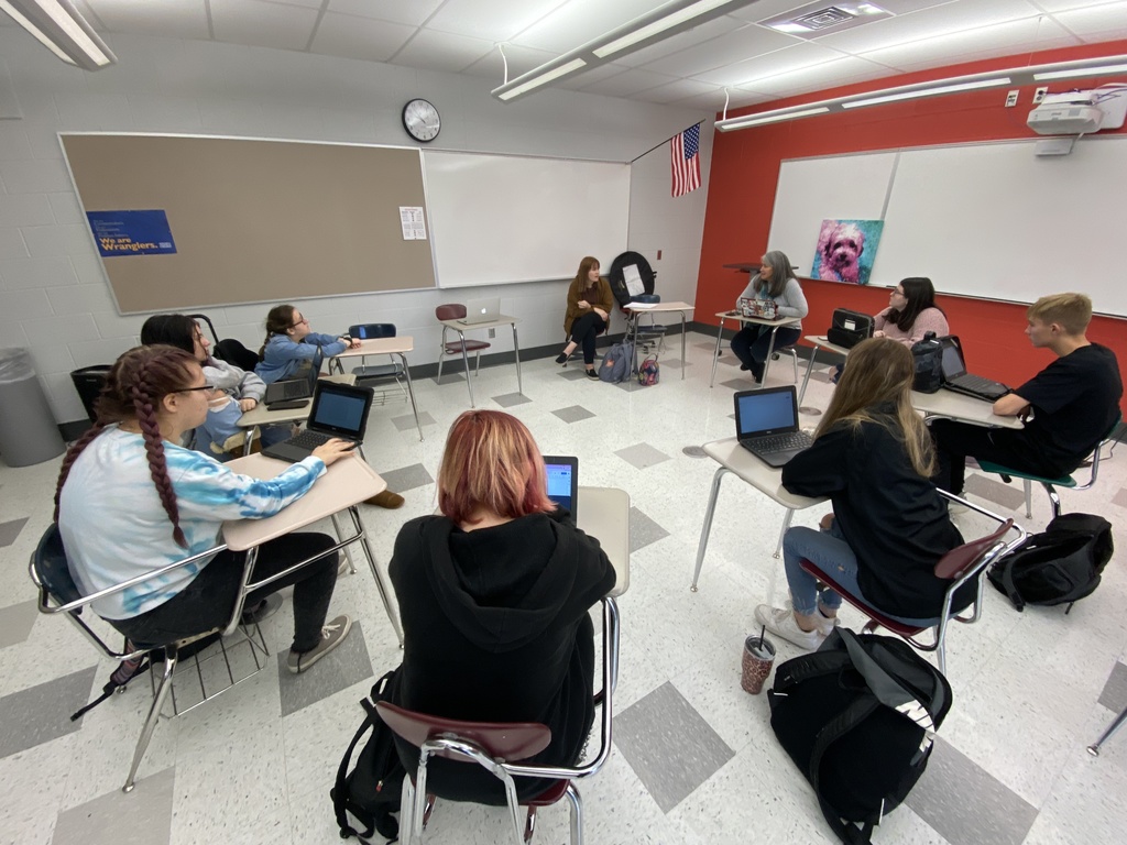 students sitting in a circle talking with a teacher