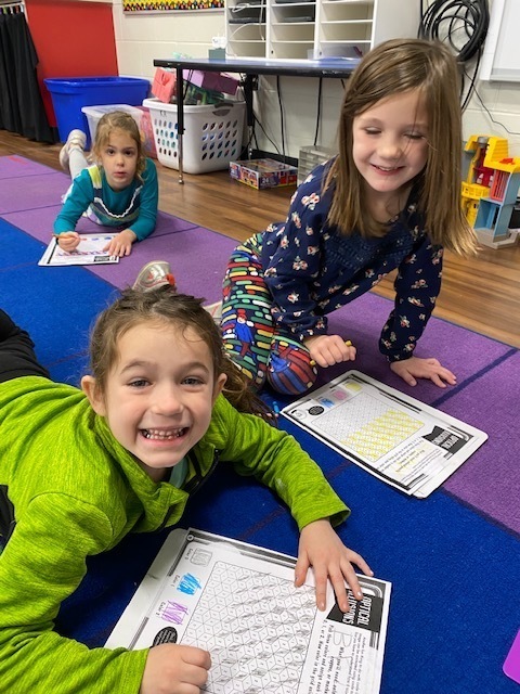 Kindergarten students coloring an optical illusion paper
