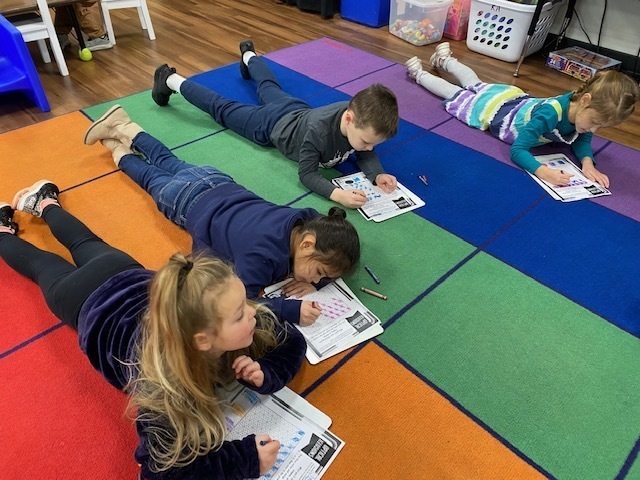 Kindergarten students coloring an optical illusion paper