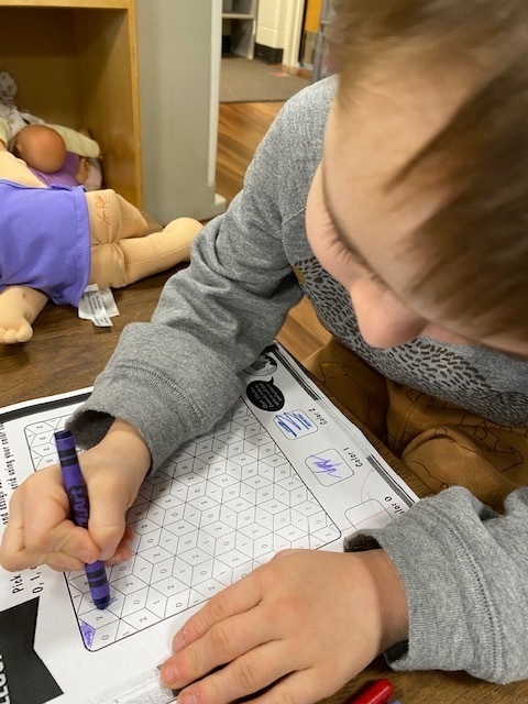 Kindergarten students coloring an optical illusion paper