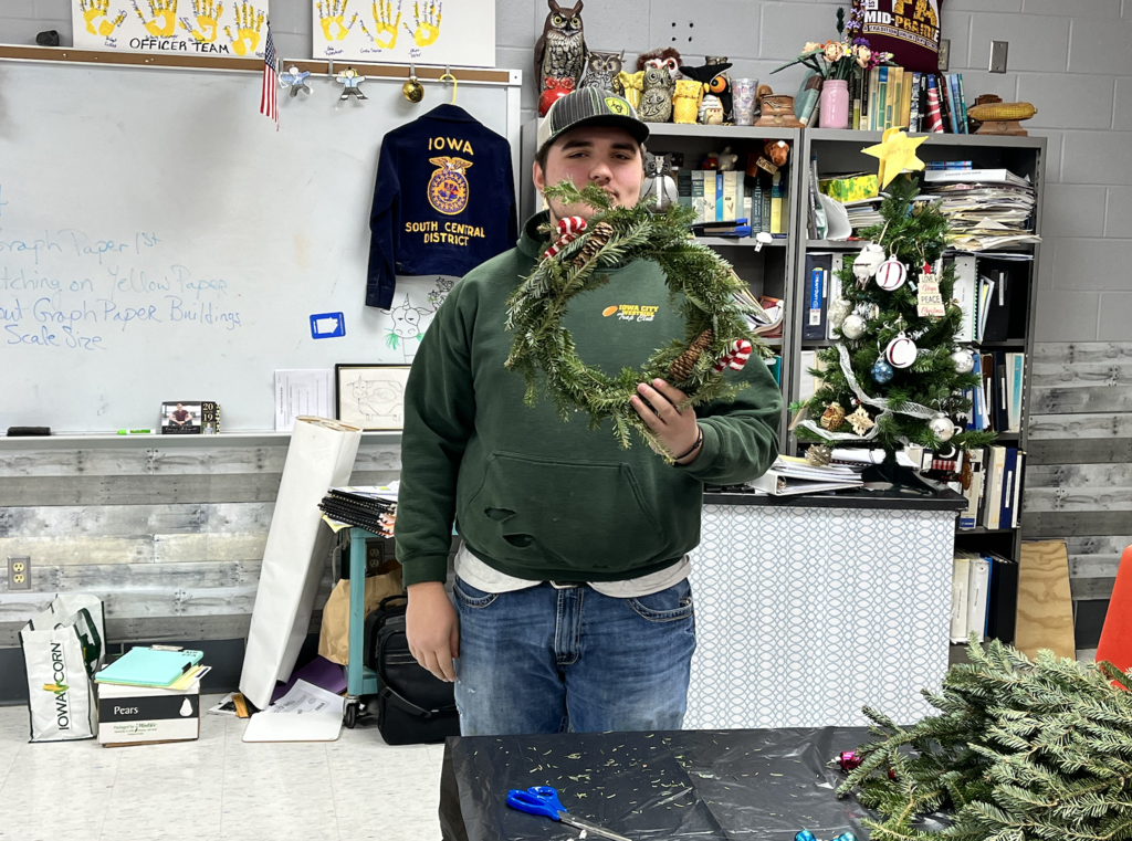 Student holding up his holiday wreath