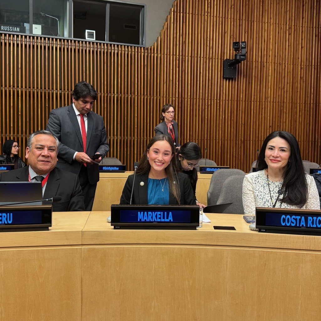 1 man and 2 women sitting at table with microphone