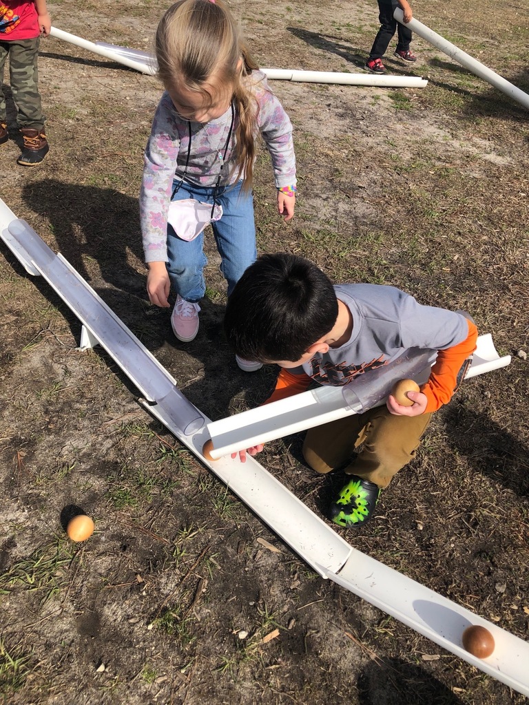 Two kids are working together to get the wooden ball to keep moving on the ramp.