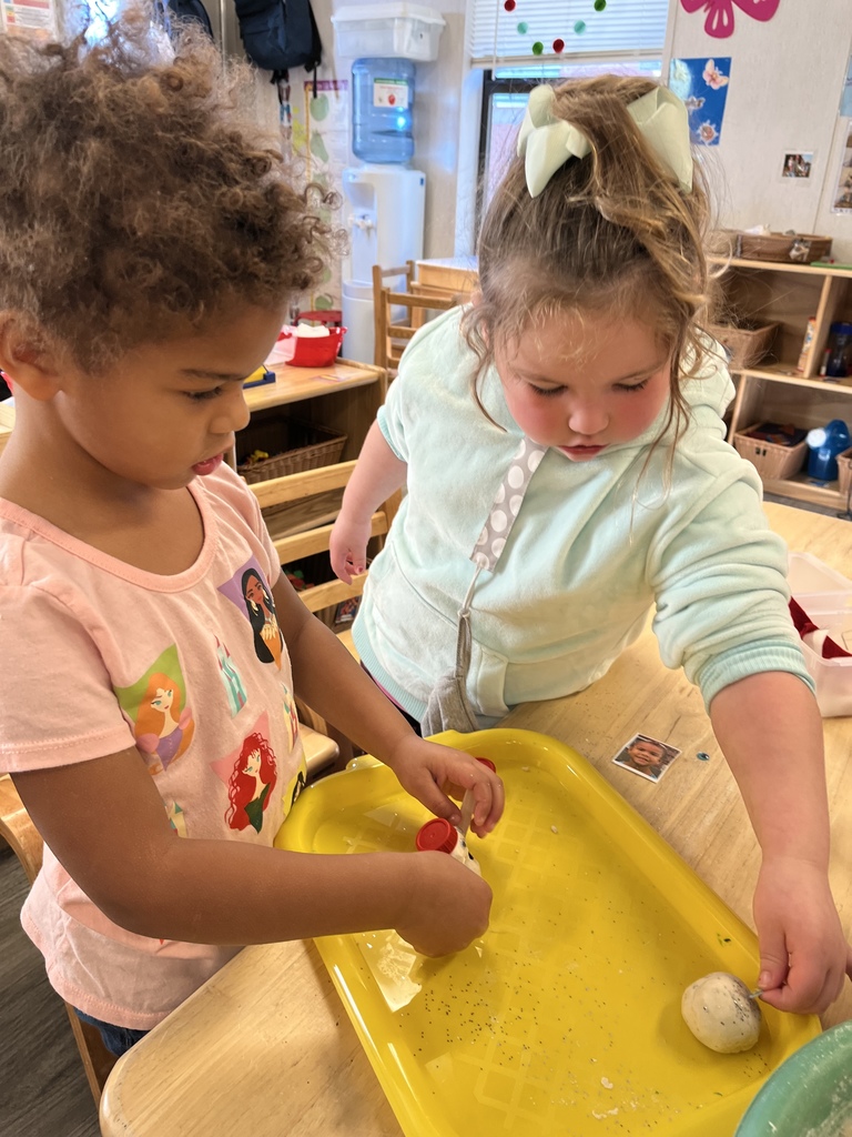 Two girls are working together to create a snowman out of dough.