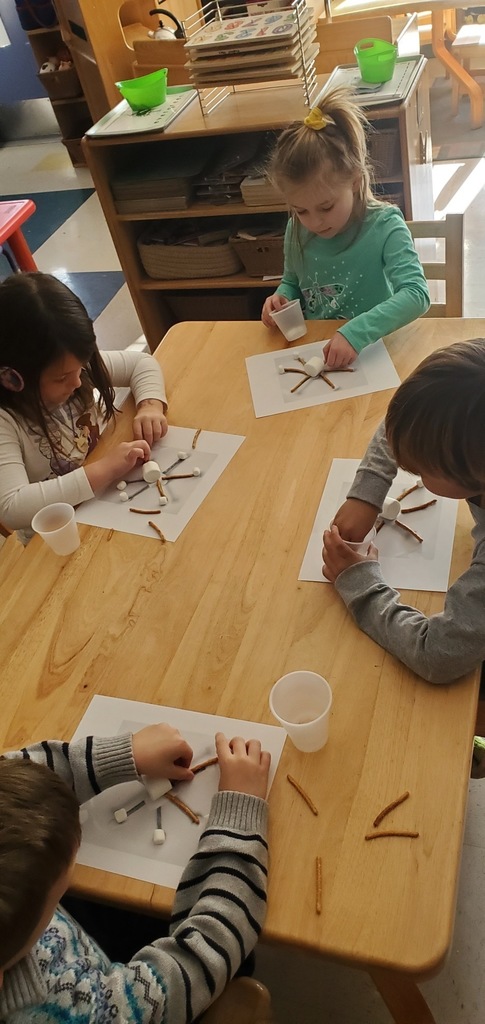 The kids at the table are working hard at making snowflakes with pretzels and marshmallows.