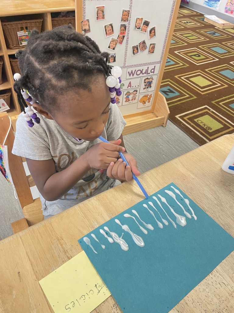This little girl is working hard, blowing through a straw to make icicles on her paper.