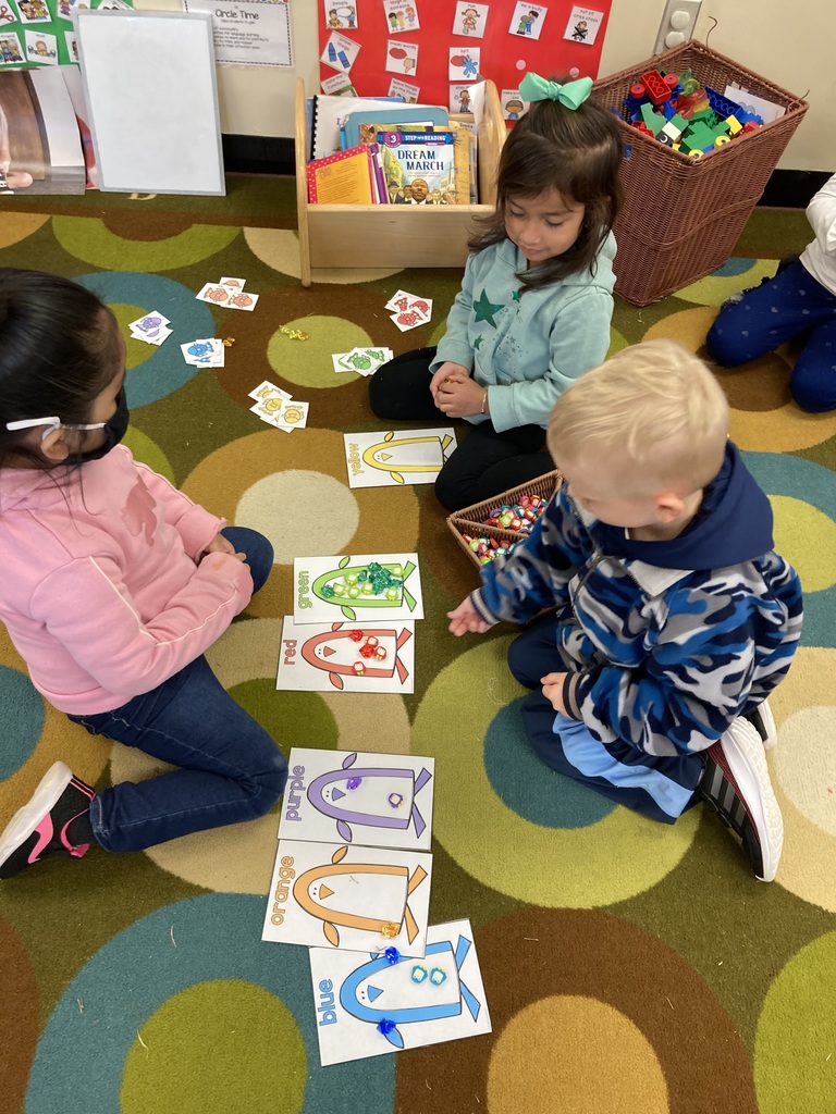 Three kids are sorting penguins by color.