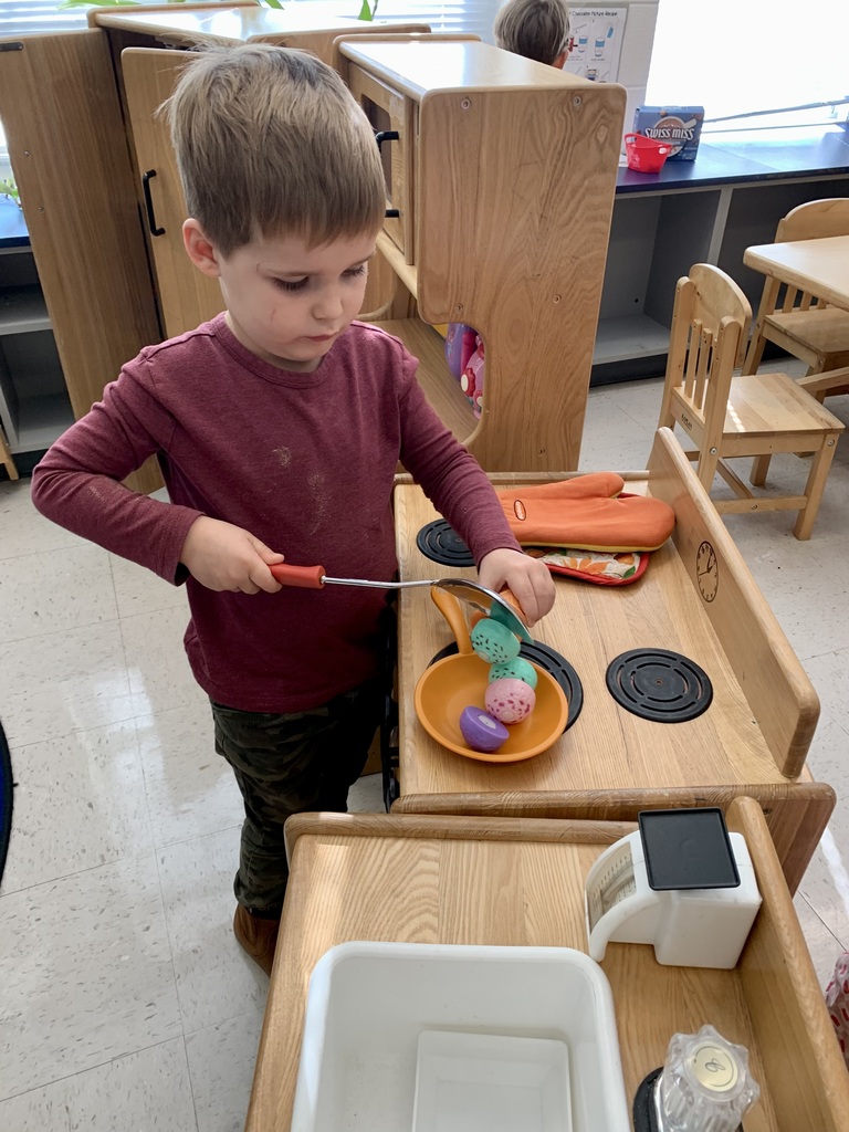 One little boy is slicing off ice cream scoops into a pan in the Dramatic Play center.