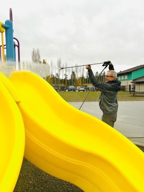 PUD Team member pressure washing the slide in CCP playground
