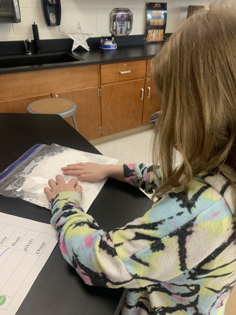 Student practicing writing words in snow.