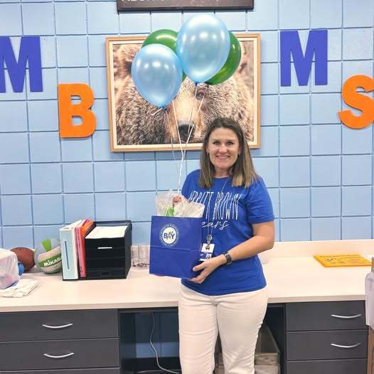 Dr. Hart holding balloons and a gift.