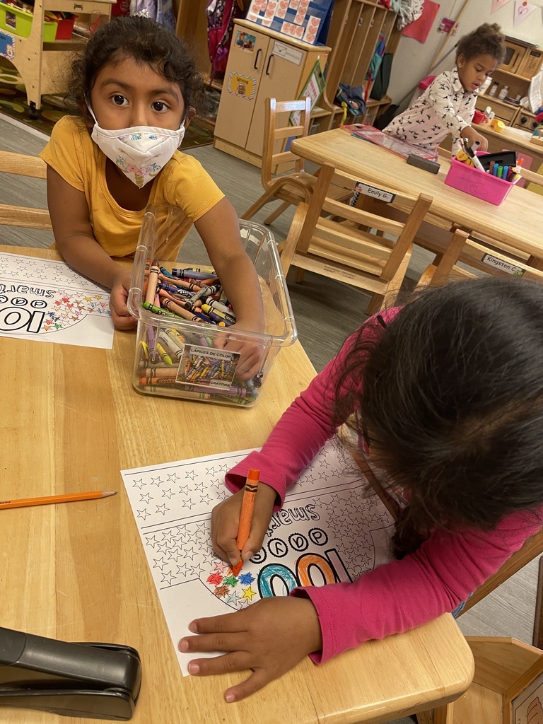 Two girls are coloring in their 100 Days Smarter headband.
