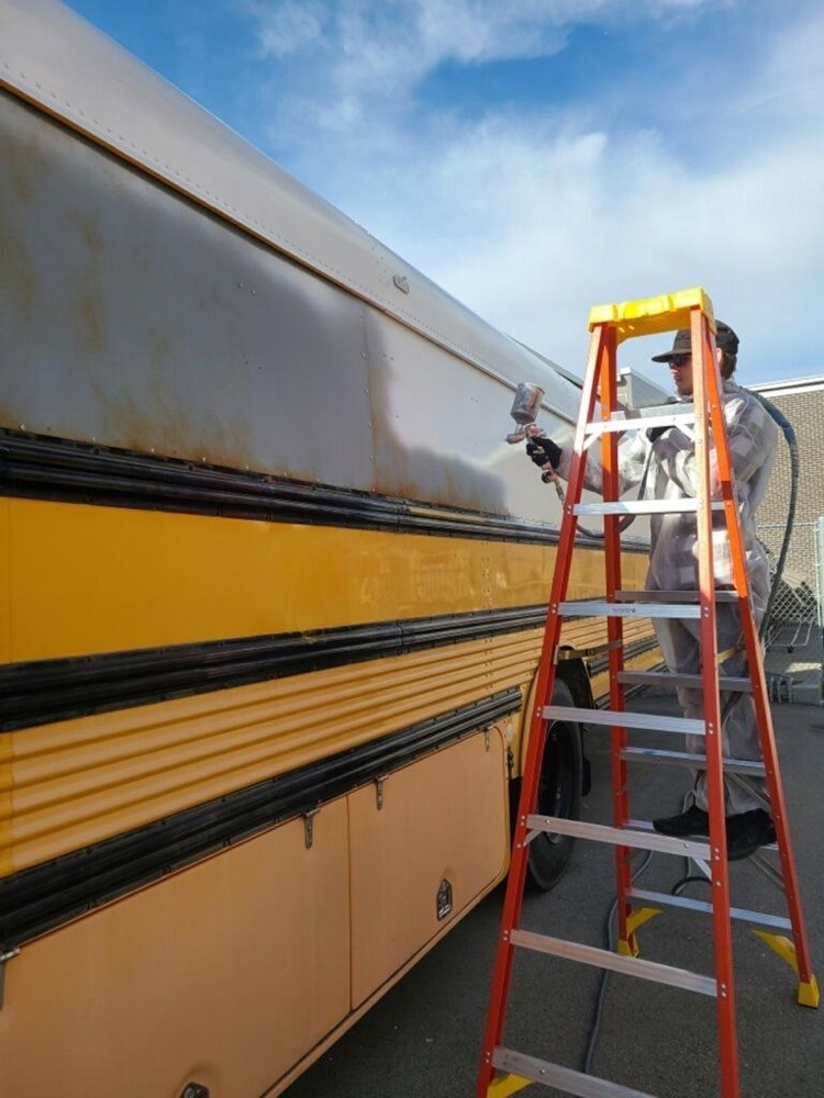 student painting a bus