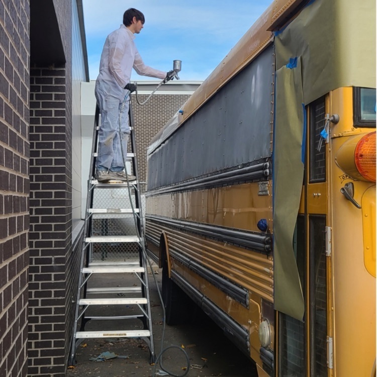 student painting a bus
