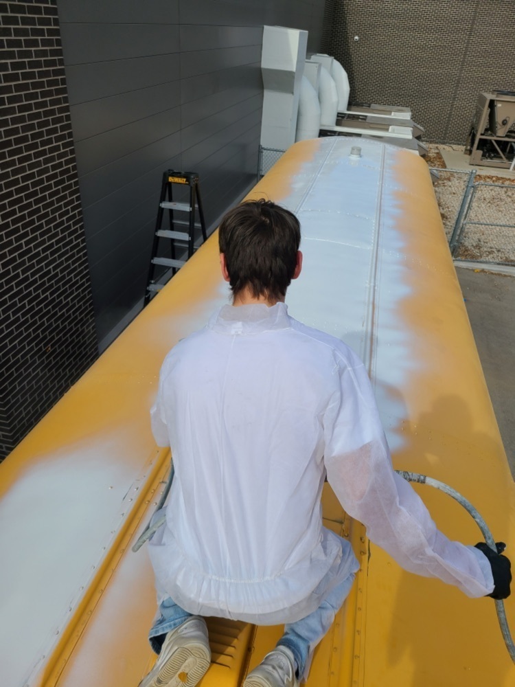 student painting a bus
