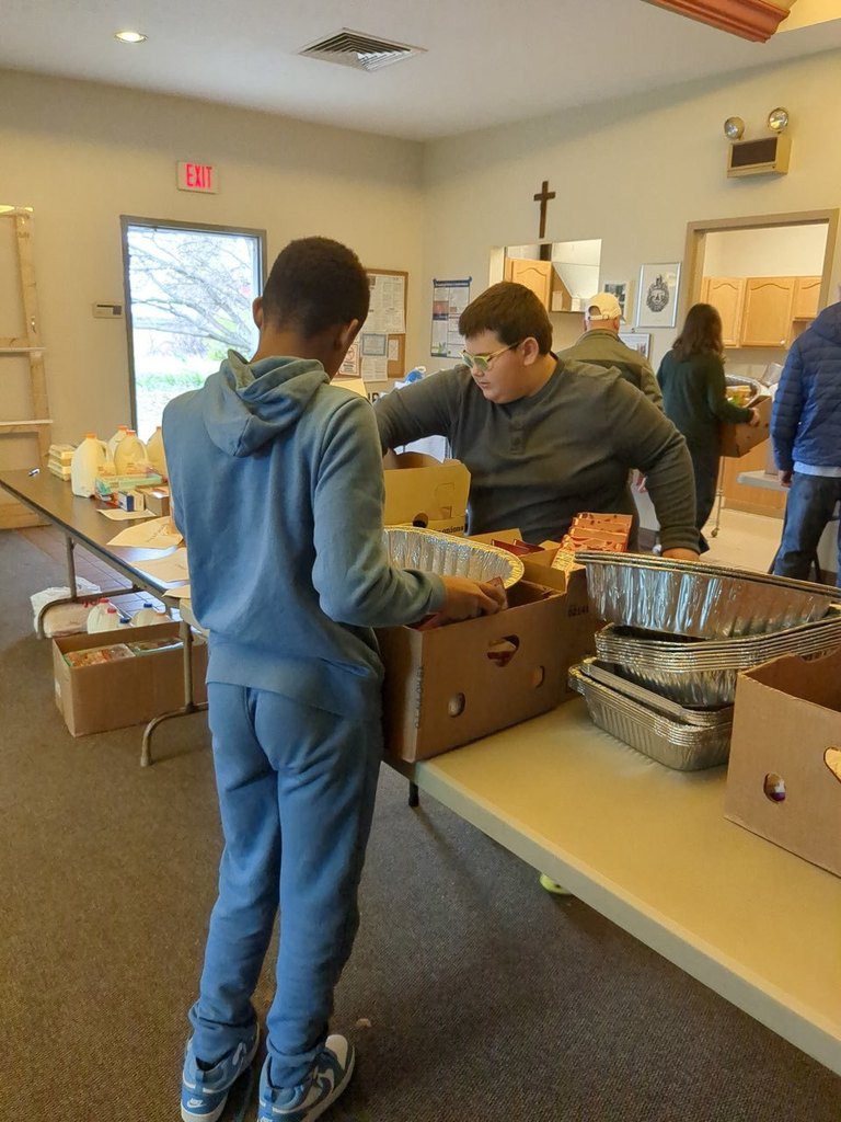 Two boys at long table fillin banana boxes.