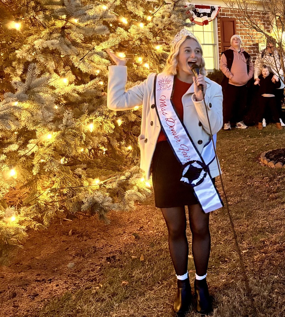 young woman in front of a lit Christmas tree