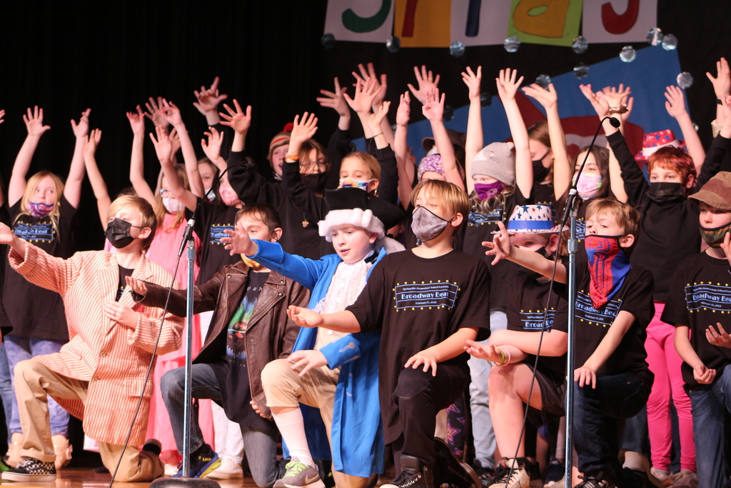 Students on stage with their hands in the air.
