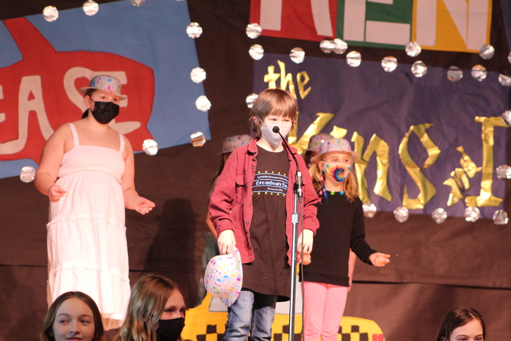 A boy sings in front of a microphone